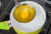 Egg being poured into boiling water